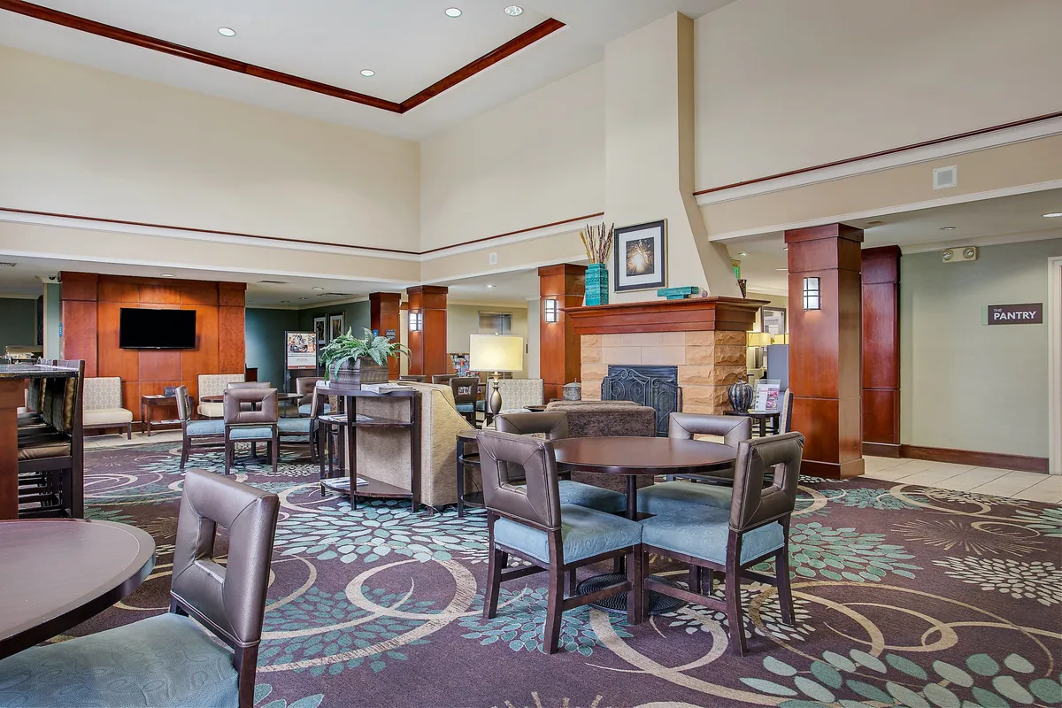 A cozy seating area centered around a fireplace, featuring soft lighting, decorative plants, and a television. The space feels warm and inviting, designed for socializing, enjoying quiet moments together, or relaxing in comfort after a busy day in the city.