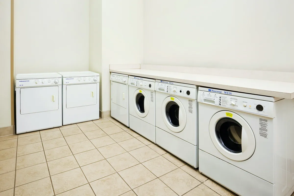 A practical laundry room with multiple washing machines, dryers, and a countertop for folding clothes. The space is functional and well-organized, making it easy for guests to stay fresh during longer visits.